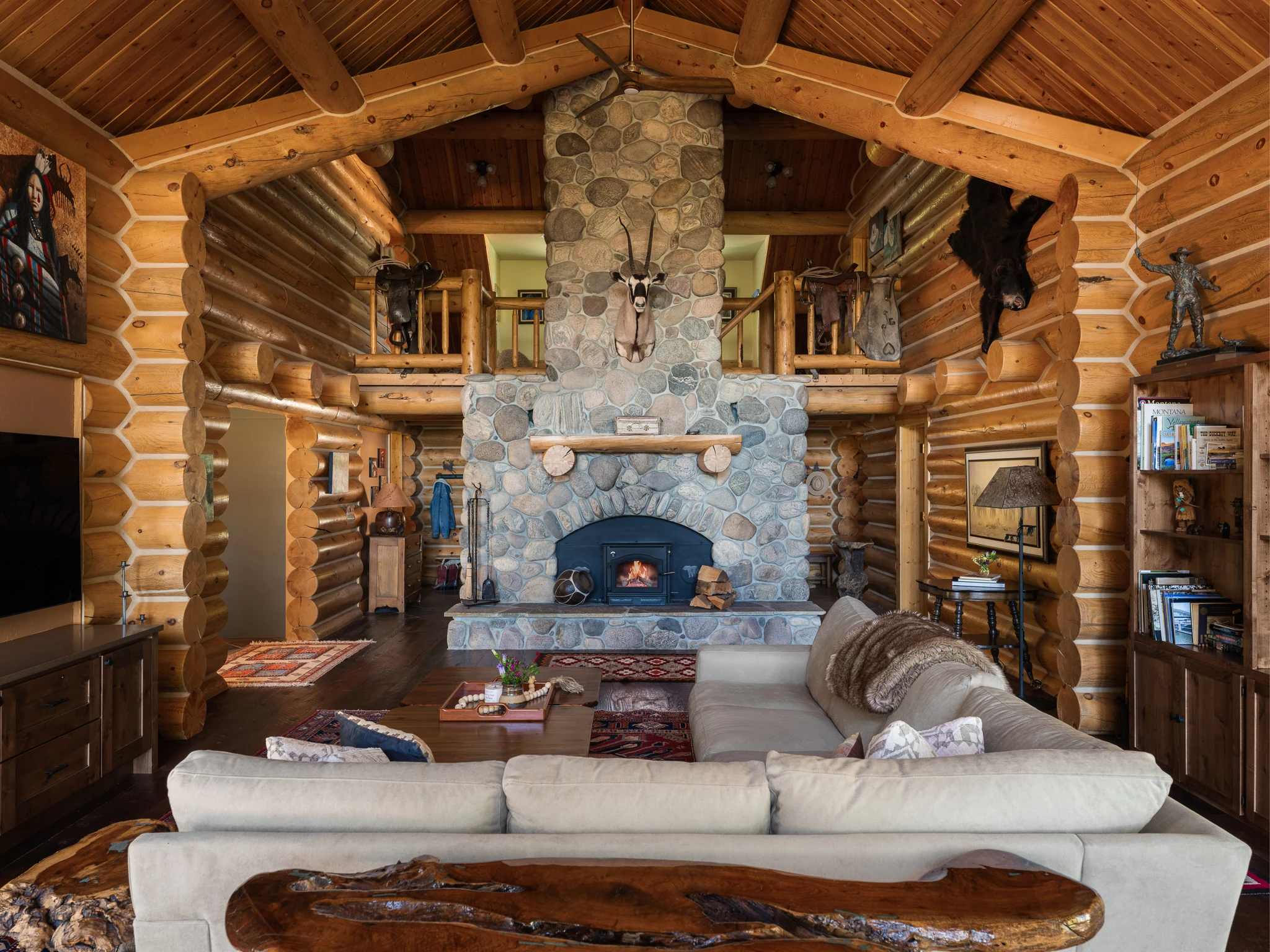 Great room with river-rock fireplace, sectional sofa, and mounted taxidermy — interior design photography Livingston Montana, Sam Schlauch Designs